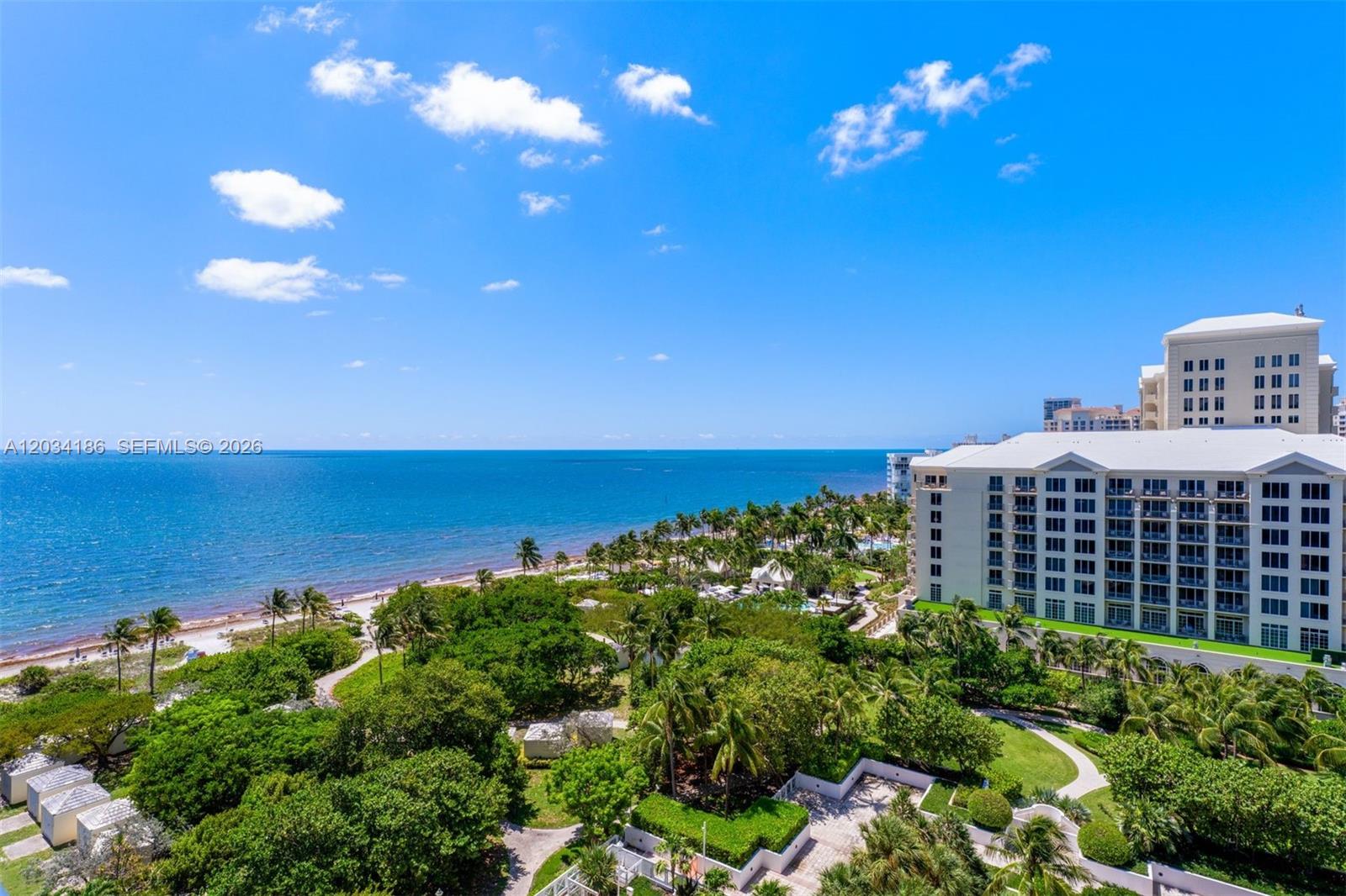 An elevated view shows a beach, lush tropical landscaping, and a large multi-story building — 430 Grand Bay Drive # 1103, Key Biscayne FL 33149, KEY BISCAYNE, FL