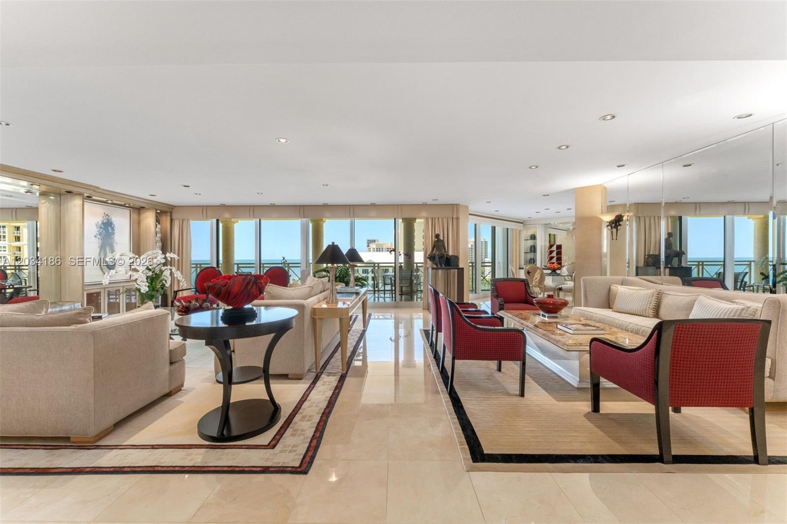 A spacious living room features beige sofas, red accent chairs, marble floors, and floor-to-ceiling windows — 430 Grand Bay Drive # 1103, Key Biscayne FL 33149, KEY BISCAYNE, FL