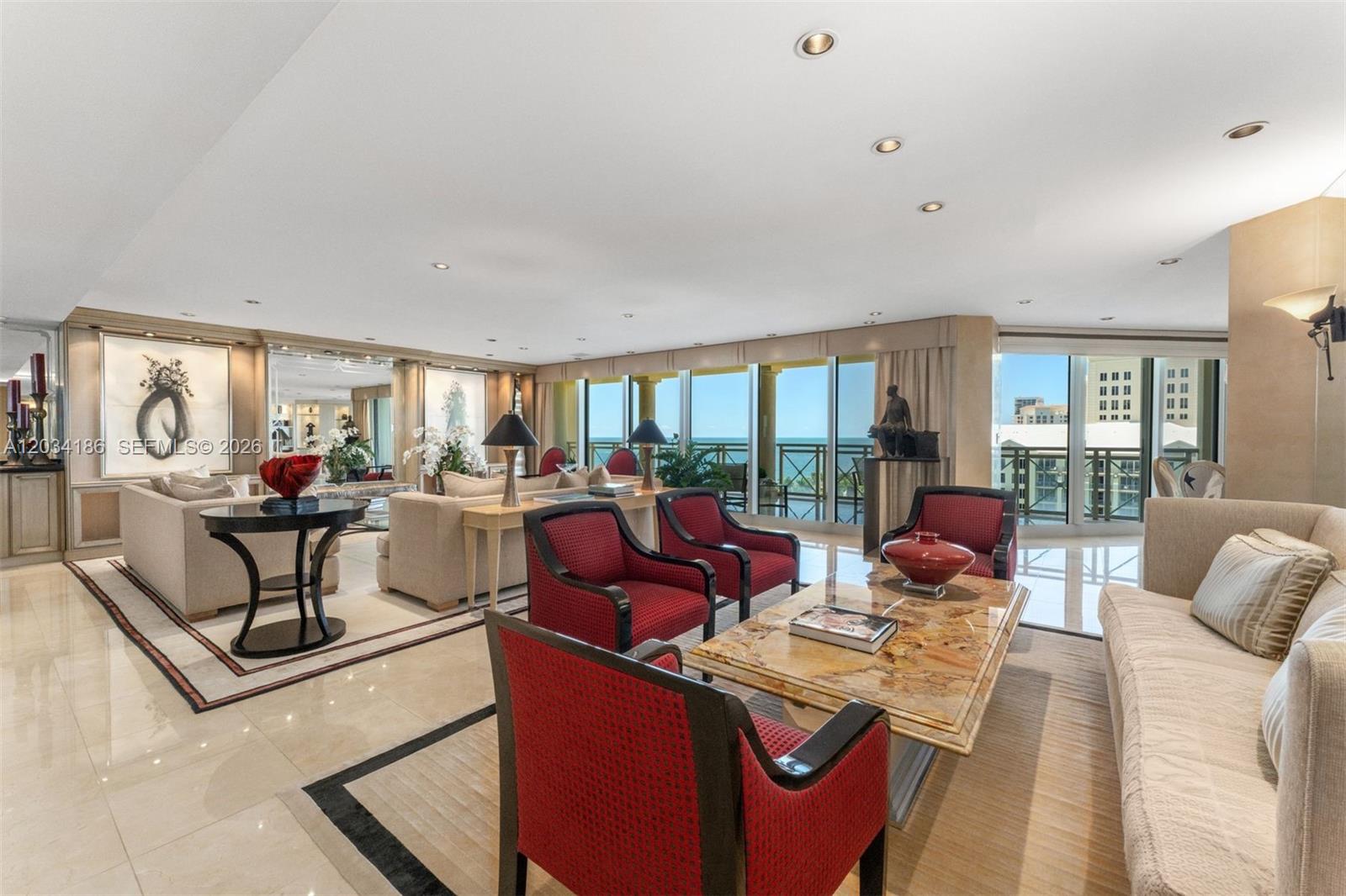 A spacious living room features beige sofas, red armchairs, marble floors, and floor-to-ceiling windows — 430 Grand Bay Drive # 1103, Key Biscayne FL 33149, KEY BISCAYNE, FL