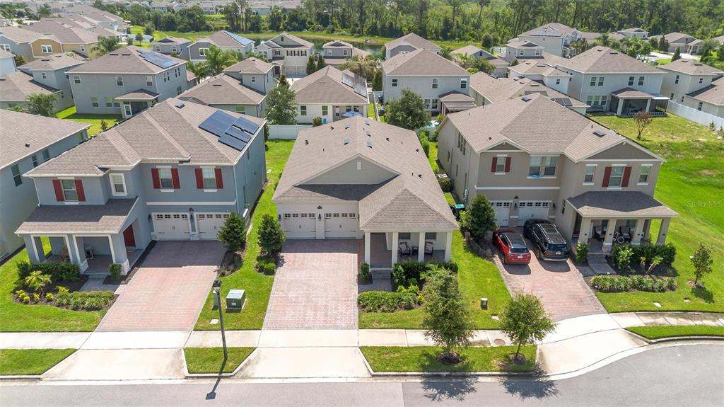 An aerial view shows three suburban houses with paved driveways and green lawns — 11043 JACKSON COVE, WINTER GARDEN, FL