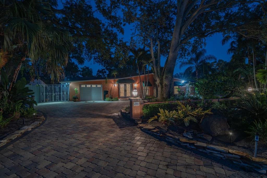 A paved driveway leads to a single-story house with a garage at night — 3033 82ND WAY N, ST PETERSBURG, FL