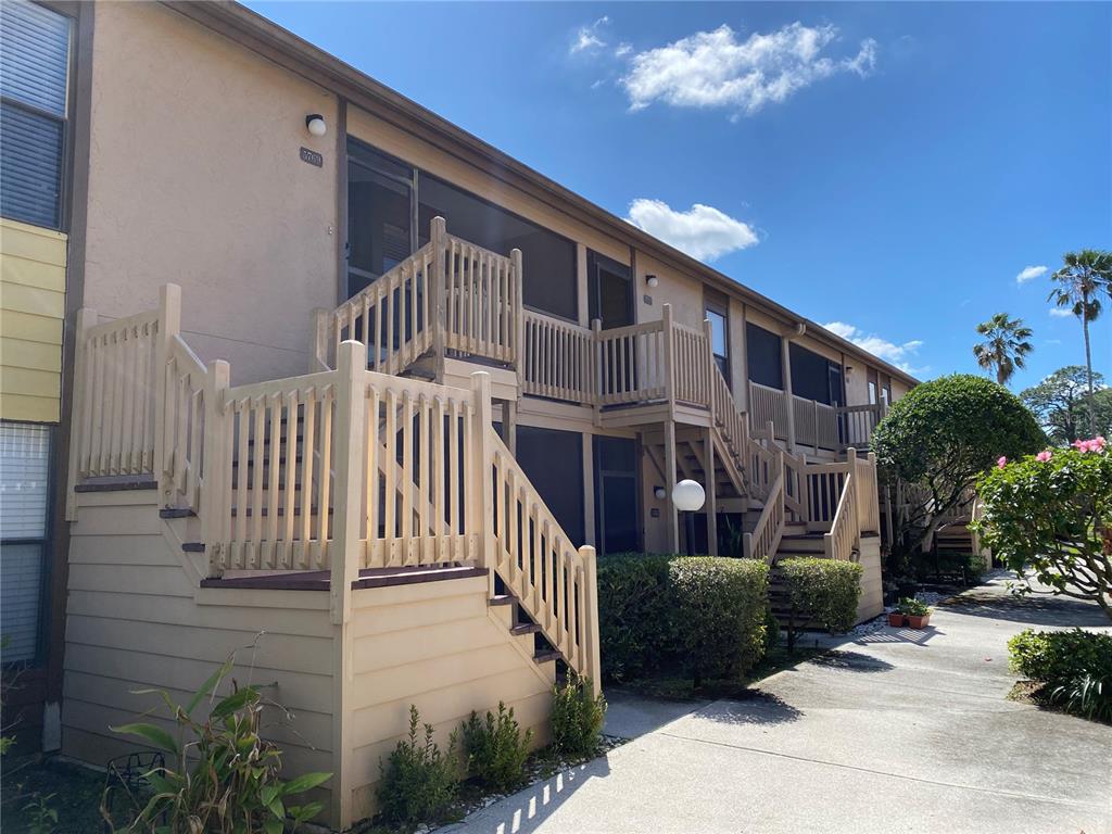 Exterior view of a two-story apartment building with wooden staircases and screened-in balconies — 5769 AVISTA DRIVE UNIT 5769, SARASOTA, FL
