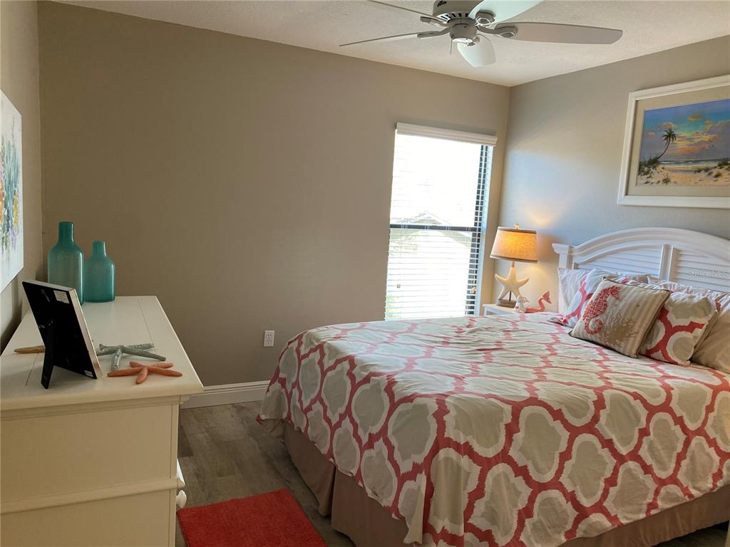 A bedroom features a bed with a patterned comforter, a white dresser, and a ceiling fan — 5769 AVISTA DRIVE UNIT 5769, SARASOTA, FL