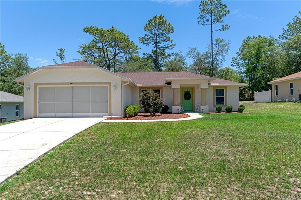 A single-story house with a two-car garage, a green front door, and a grassy lawn — 8429 N TINY LILY DRIVE, CITRUS SPRINGS, FL