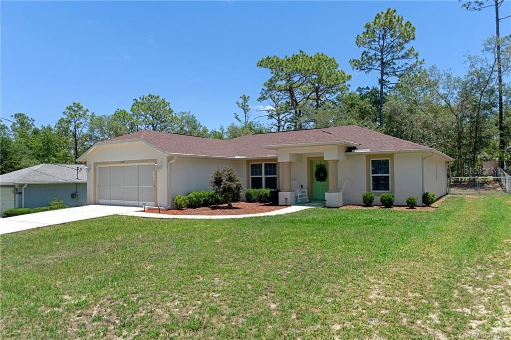 A single-story house with a beige exterior, a two-car garage, and a green front door — 8429 N TINY LILY DRIVE, CITRUS SPRINGS, FL