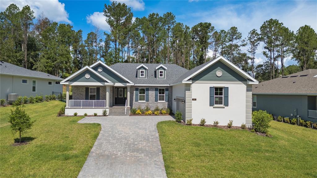 A single-story house with a brick and stucco exterior, a paved driveway, and a front porch — 3926 SOUTHERN VALLEY LOOP, BROOKSVILLE, FL