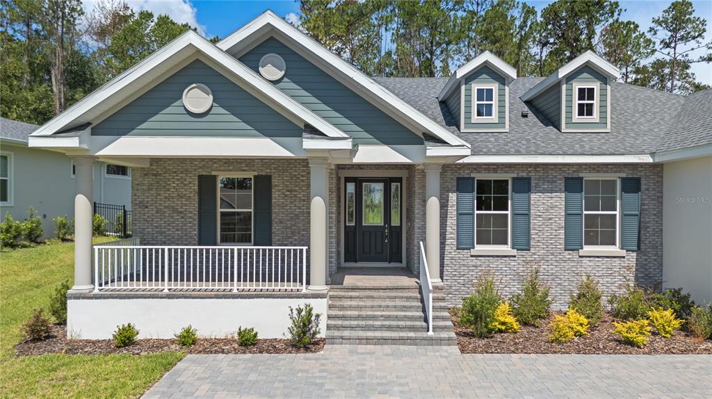 A single-story house features a brick facade, a front porch, and blue-gray siding — 3926 SOUTHERN VALLEY LOOP, BROOKSVILLE, FL