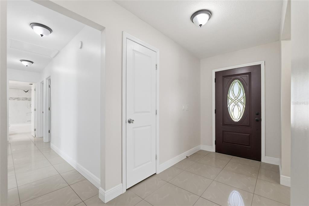 A bright entryway features light tile flooring, a dark brown front door, and white walls — 11807 NICKLAUS CIRCLE, TAMPA, FL