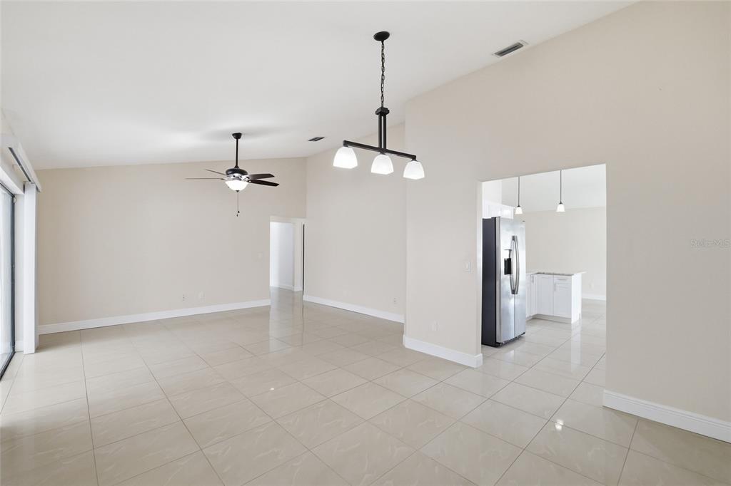 An open-concept living area with light tile flooring, a ceiling fan, and a dining light — 11807 NICKLAUS CIRCLE, TAMPA, FL