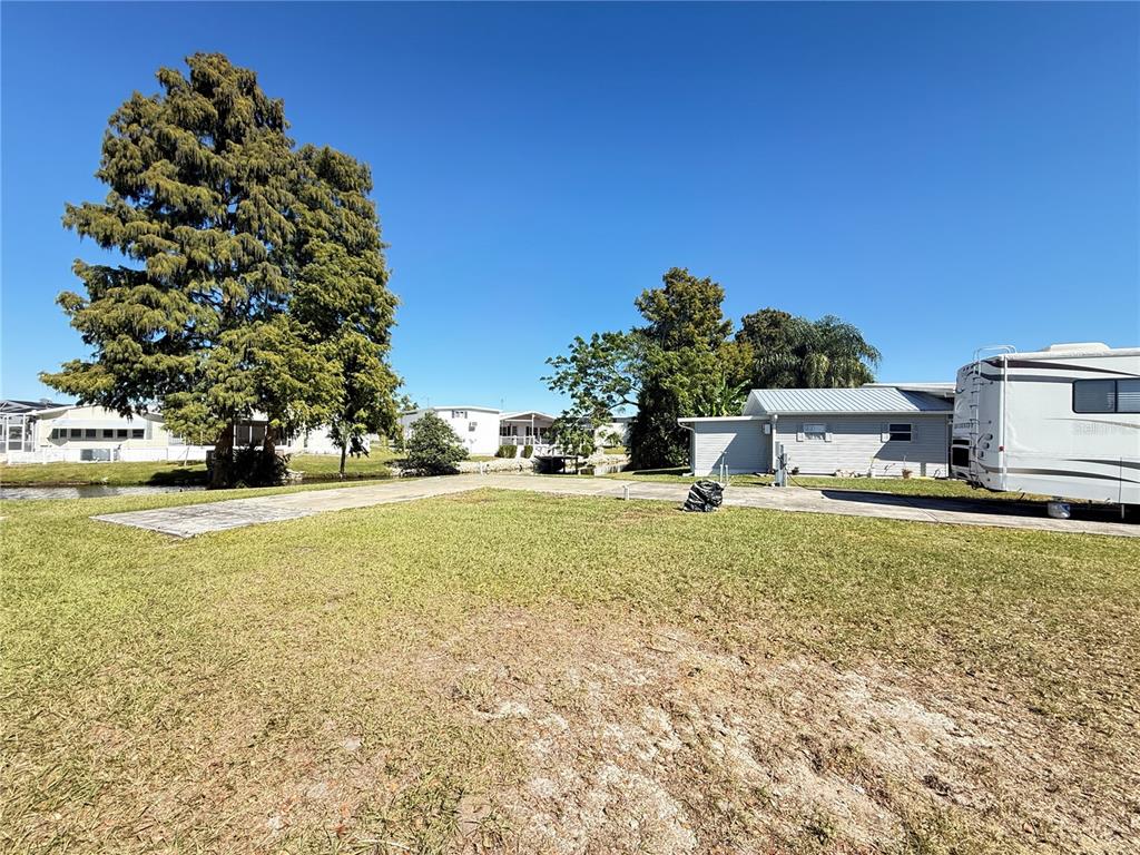 A grassy lot features a concrete pad, a large tree, and a parked recreational vehicle — 5058 SHORE LINE DRIVE, POLK CITY, FL