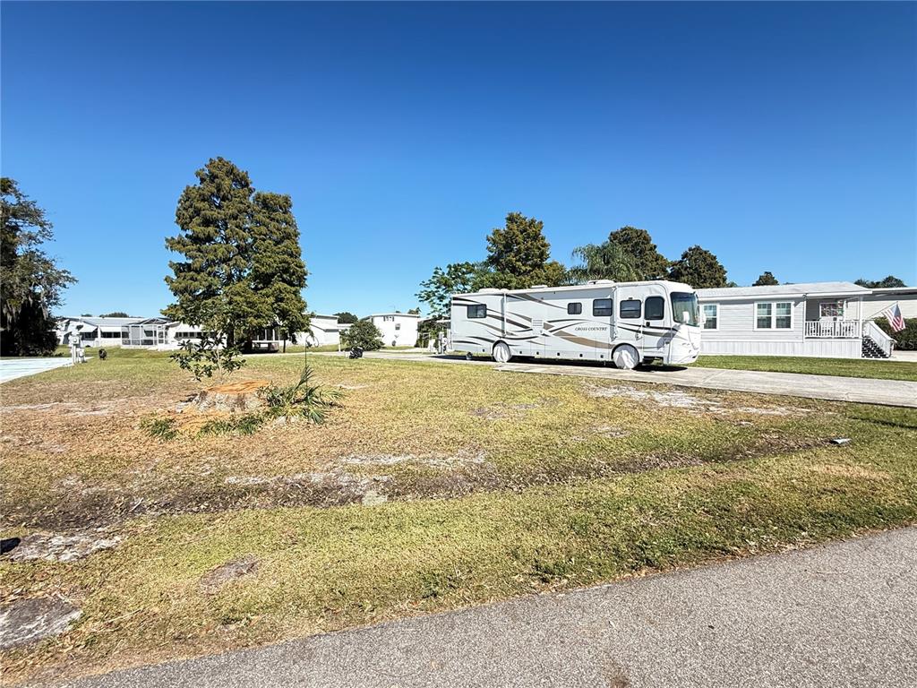 A large motorhome is parked on a concrete driveway next to a manufactured home — 5058 SHORE LINE DRIVE, POLK CITY, FL