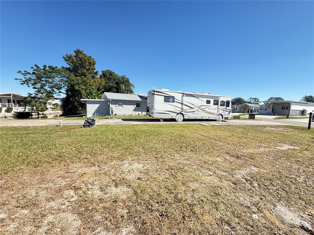 A large recreational vehicle is parked on a concrete pad next to a small house — 5058 SHORE LINE DRIVE, POLK CITY, FL