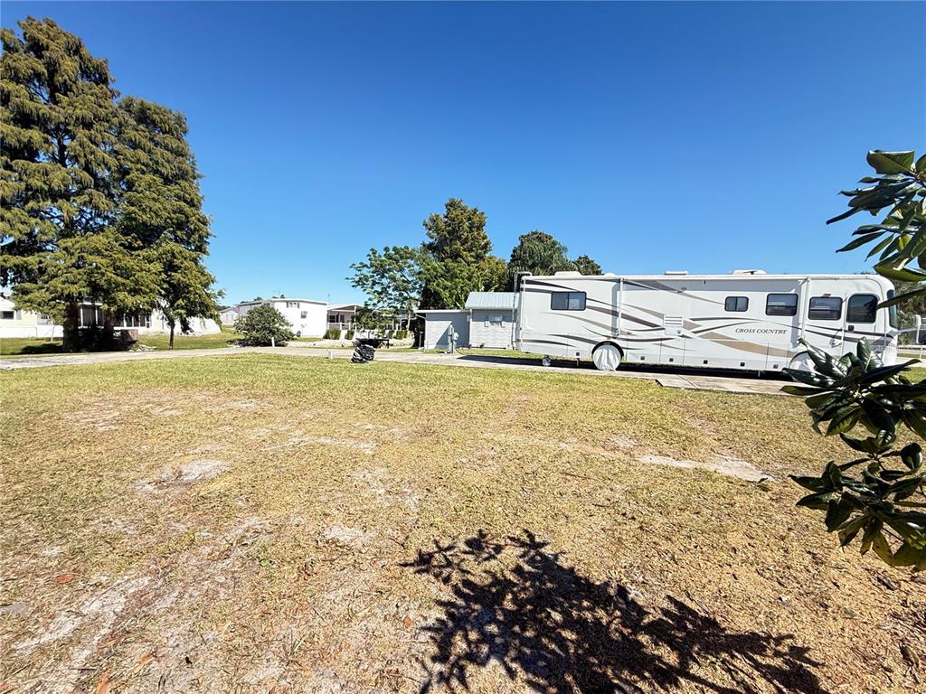 A large recreational vehicle is parked on a grassy lot next to a small building — 5058 SHORE LINE DRIVE, POLK CITY, FL