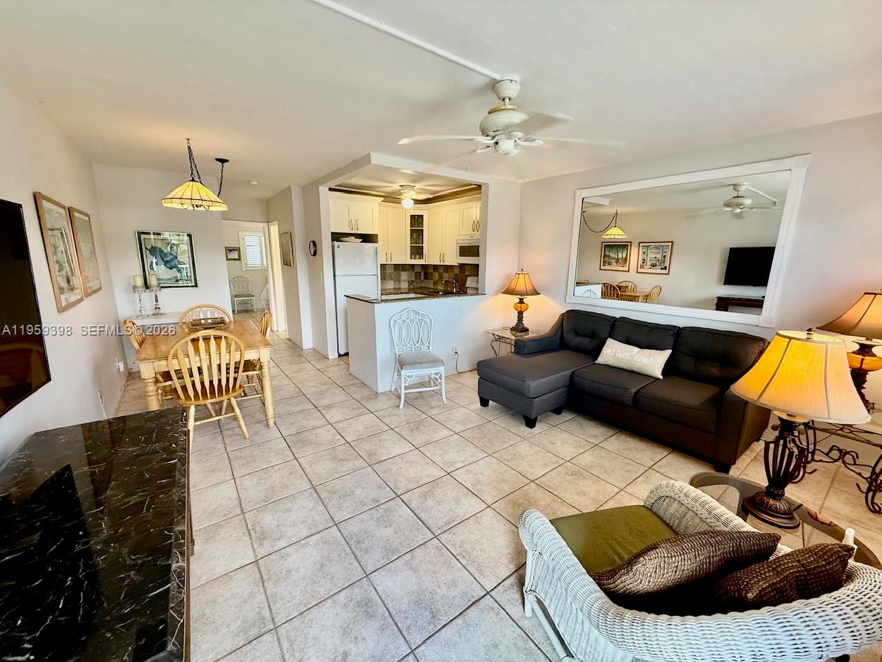 An open-concept living and dining area features tile flooring, a kitchen, and a sectional sofa — 301 E Mcnab Rd # 205, Pompano Beach FL 33060, POMPANO BEACH, FL