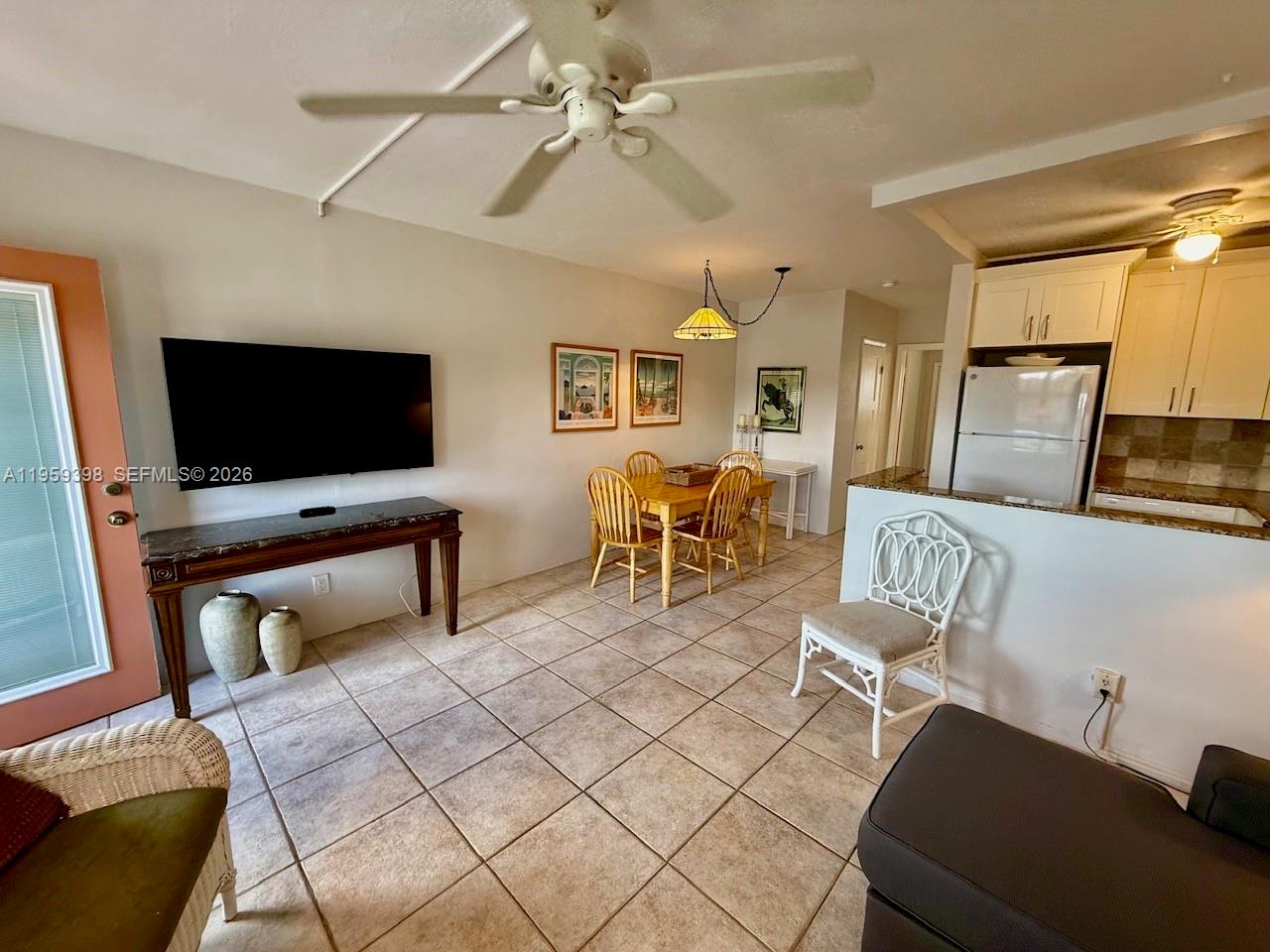 This open-concept living and dining area features tile flooring, a ceiling fan, and kitchen access — 301 E Mcnab Rd # 205, Pompano Beach FL 33060, POMPANO BEACH, FL