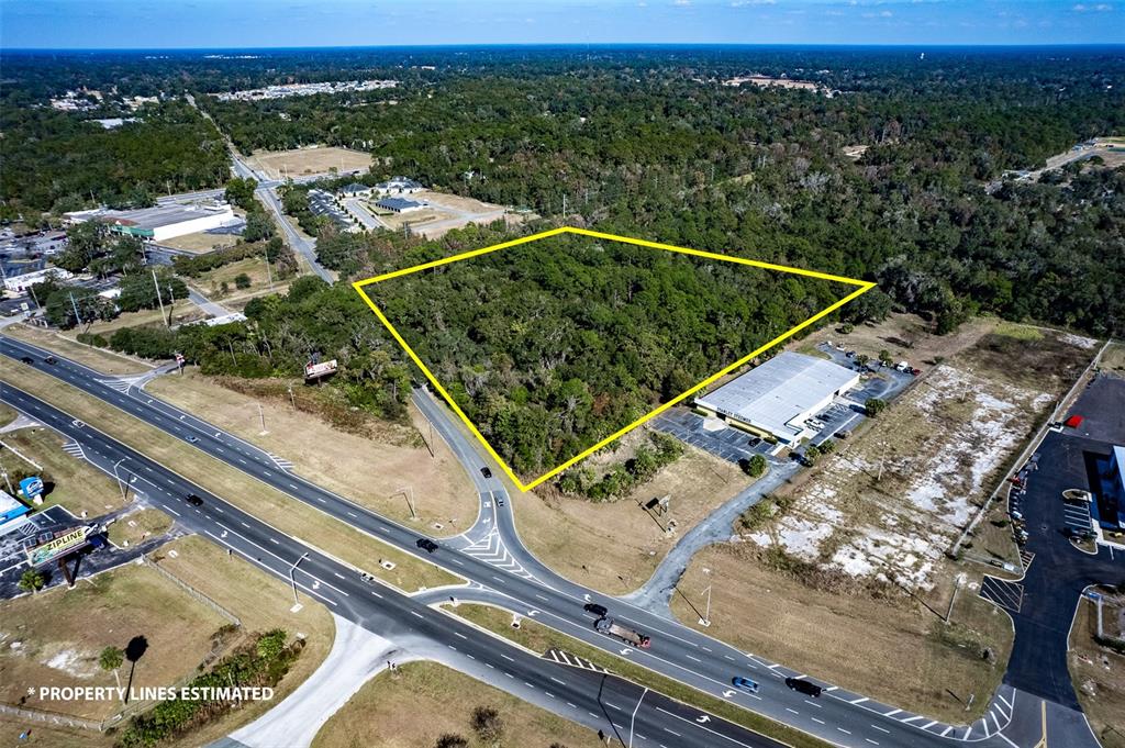 An aerial view shows a wooded, trapezoidal plot of land outlined in yellow near a highway — HWY 441 and W ANTHONY RD, OCALA, FL