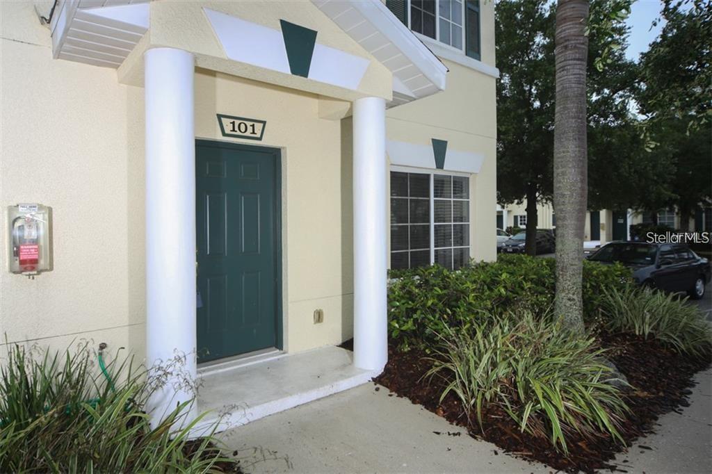 The exterior of a building entrance features a green door labeled 101 with white columns — 267 CAPE HARBOUR LOOP UNIT 101, BRADENTON, FL