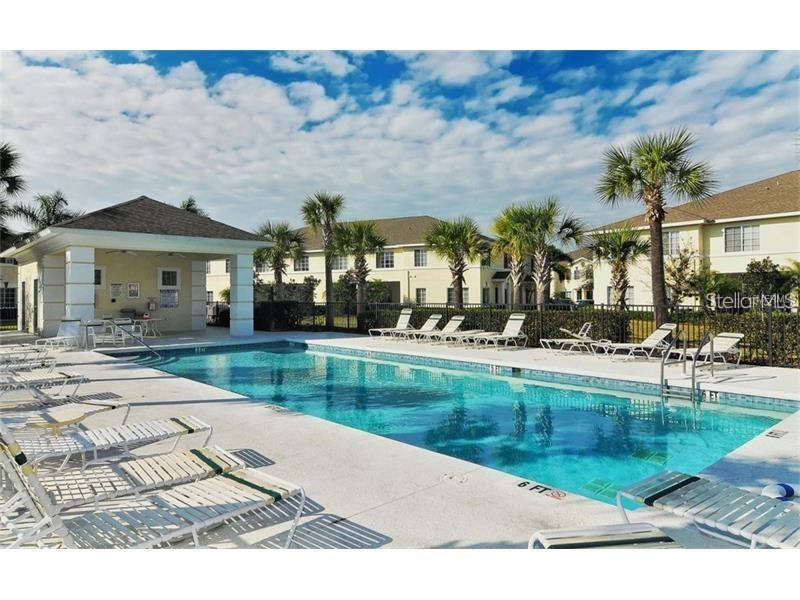 A rectangular swimming pool with lounge chairs and a covered patio area outside apartment buildings — 267 CAPE HARBOUR LOOP UNIT 101, BRADENTON, FL
