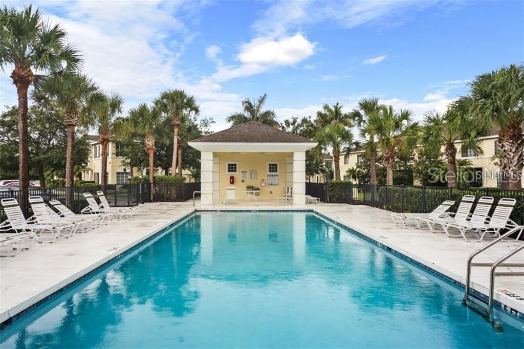 A rectangular swimming pool sits in front of a covered pavilion surrounded by palm trees — 267 CAPE HARBOUR LOOP UNIT 101, BRADENTON, FL