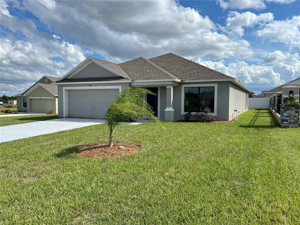 A single-story suburban house with a gray stucco exterior, a two-car garage, and a lawn — 540 CENTRAL RIDGE LANE, FROSTPROOF, FL
