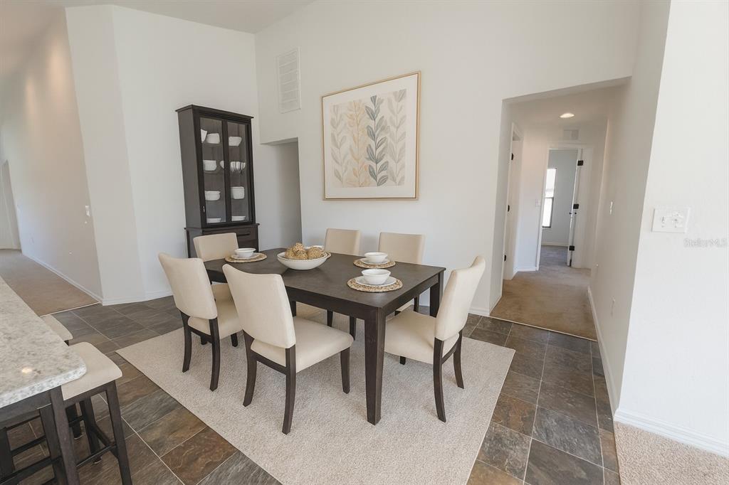 A dining room features a dark wood table with six chairs on a light rug — 540 CENTRAL RIDGE LANE, FROSTPROOF, FL
