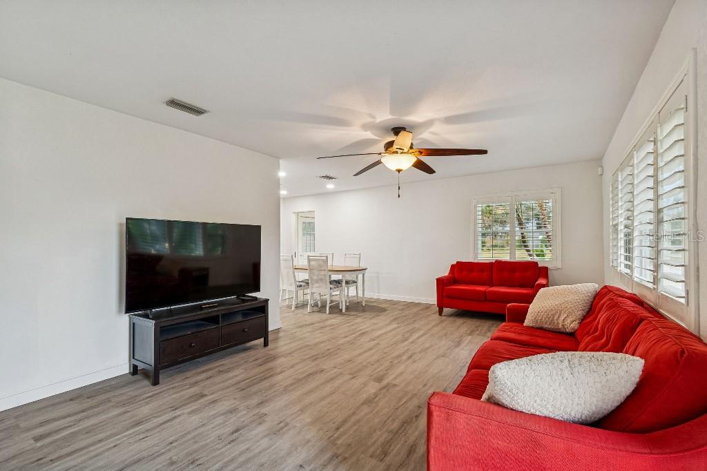 A living room features red sofas, a television on a stand, and light wood flooring — 4601 VENETIAN BOULEVARD NE, ST PETERSBURG, FL