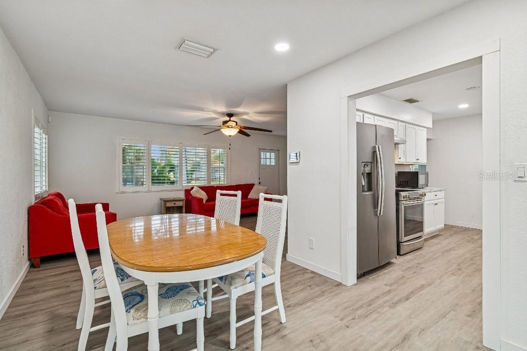 A dining area with a wooden table leads into a kitchen with stainless steel appliances — 4601 VENETIAN BOULEVARD NE, ST PETERSBURG, FL