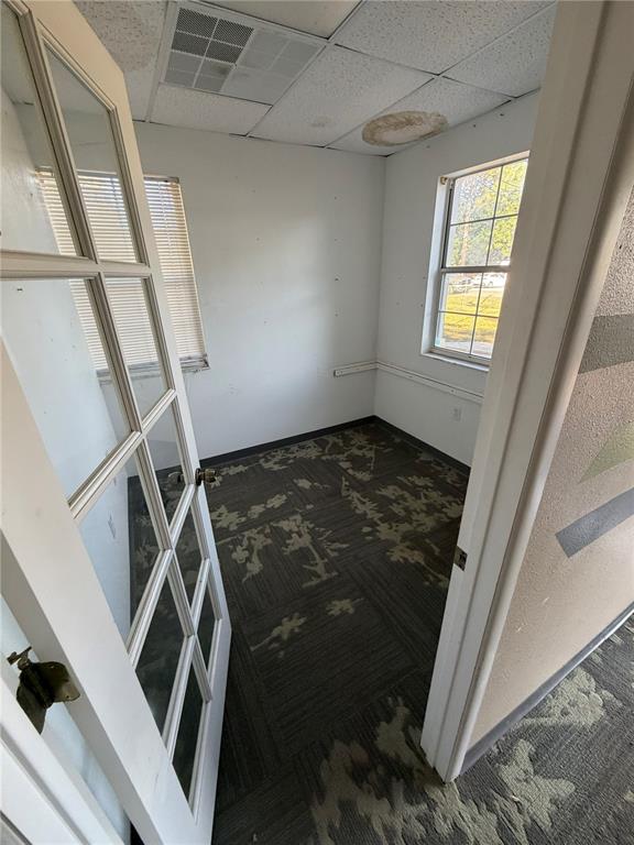 A small office with patterned carpet, white walls, two windows, and a glass-paneled door — 15500 GEORGE BOULEVARD, CLEARWATER, FL