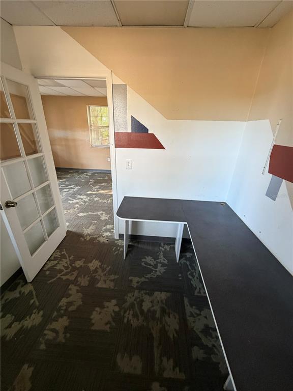 An office space features a built-in L-shaped desk, patterned carpet, and a glass-paneled door — 15500 GEORGE BOULEVARD, CLEARWATER, FL
