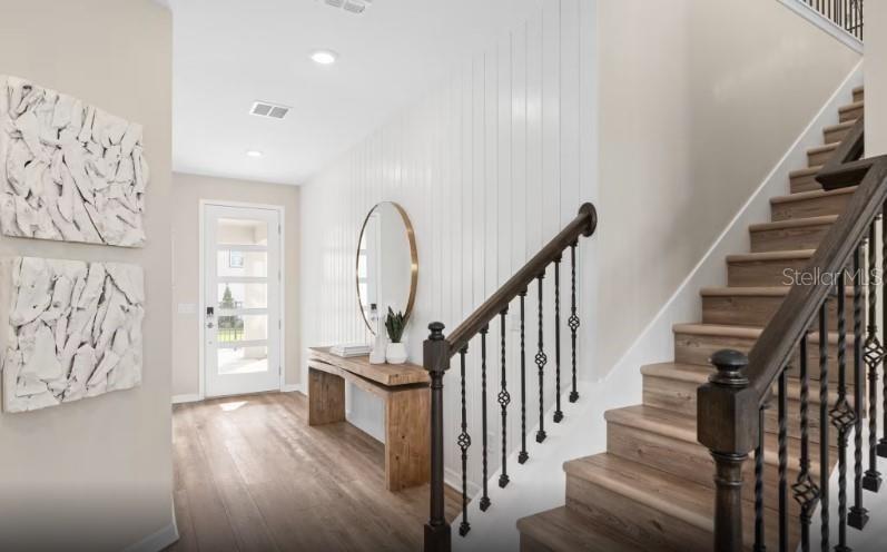 A modern living room features a sectional sofa, light wood floors, and an open kitchen — 7444 SUMMER COURT, SARASOTA, FL
