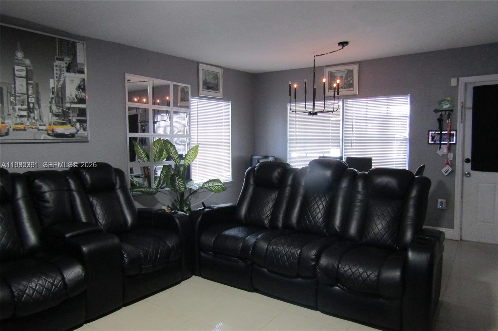A living room features black leather reclining sofas, grey walls, and a modern chandelier — 2223 NW 32nd St, Miami FL 33142, MIAMI, FL