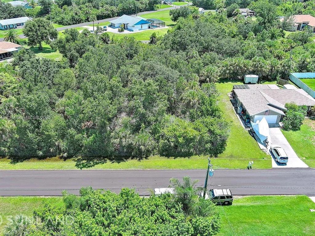 An aerial view shows a wooded vacant lot situated between two residential houses — 6264 BROOKRIDGE STREET, ENGLEWOOD, FL