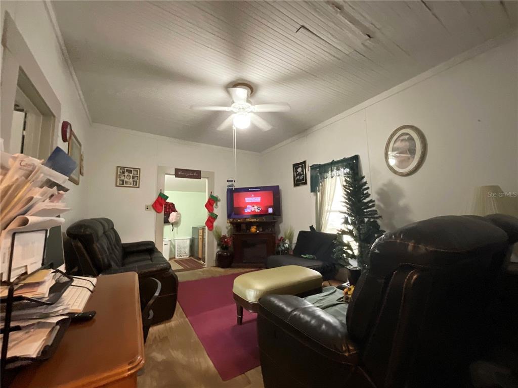 A living room features a ceiling fan, dark leather furniture, a television, and a small tree — 1701 SANFORD STREET, LAKE WALES, FL