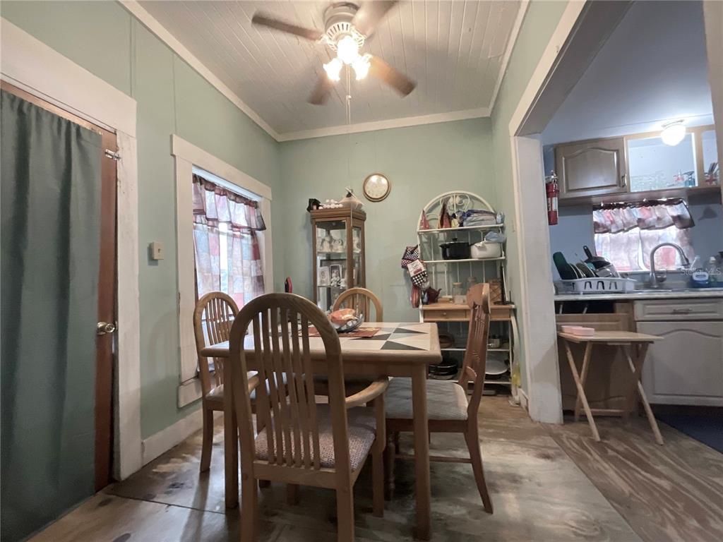 A dining area with a wooden table and chairs sits adjacent to a small kitchen — 1701 SANFORD STREET, LAKE WALES, FL