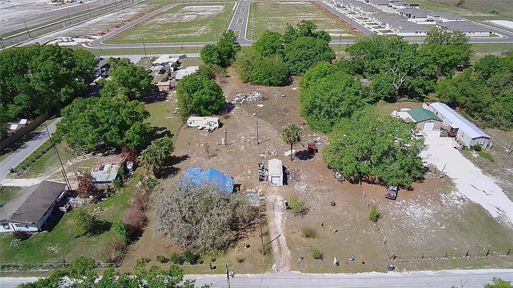 An aerial view shows a rural property with multiple structures, trees, and a dirt driveway — 1701 SANFORD STREET, LAKE WALES, FL