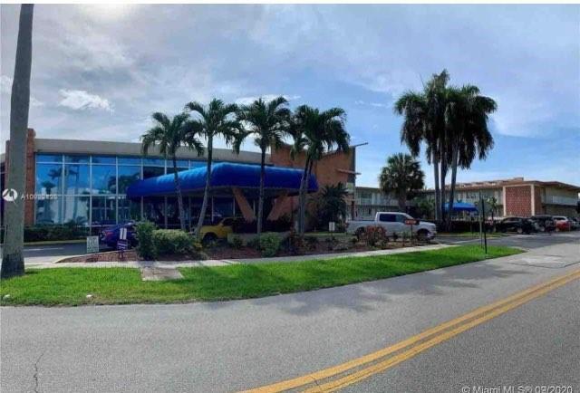 A low-rise commercial building features a blue canopy entrance and palm trees in the foreground — 26 Diplomat Parkway, FL 33009, FL