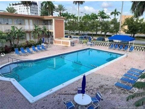 An outdoor swimming pool is surrounded by lounge chairs and a multi-story apartment building — 26 Diplomat Parkway, FL 33009, FL