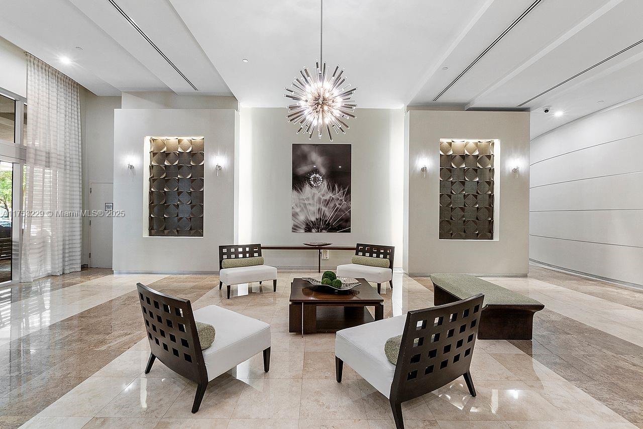 A modern lobby features a central seating area, a starburst chandelier, and two recessed wall panels — 9066 SW 73rd Ct # 1904, Miami FL 33156, MIAMI, FL