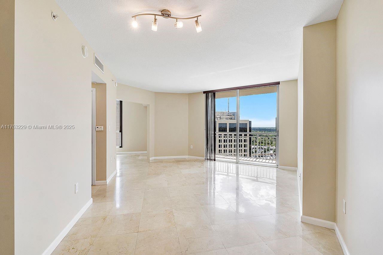 An empty living room with beige tile floors, a ceiling light fixture, and a balcony — 9066 SW 73rd Ct # 1904, Miami FL 33156, MIAMI, FL