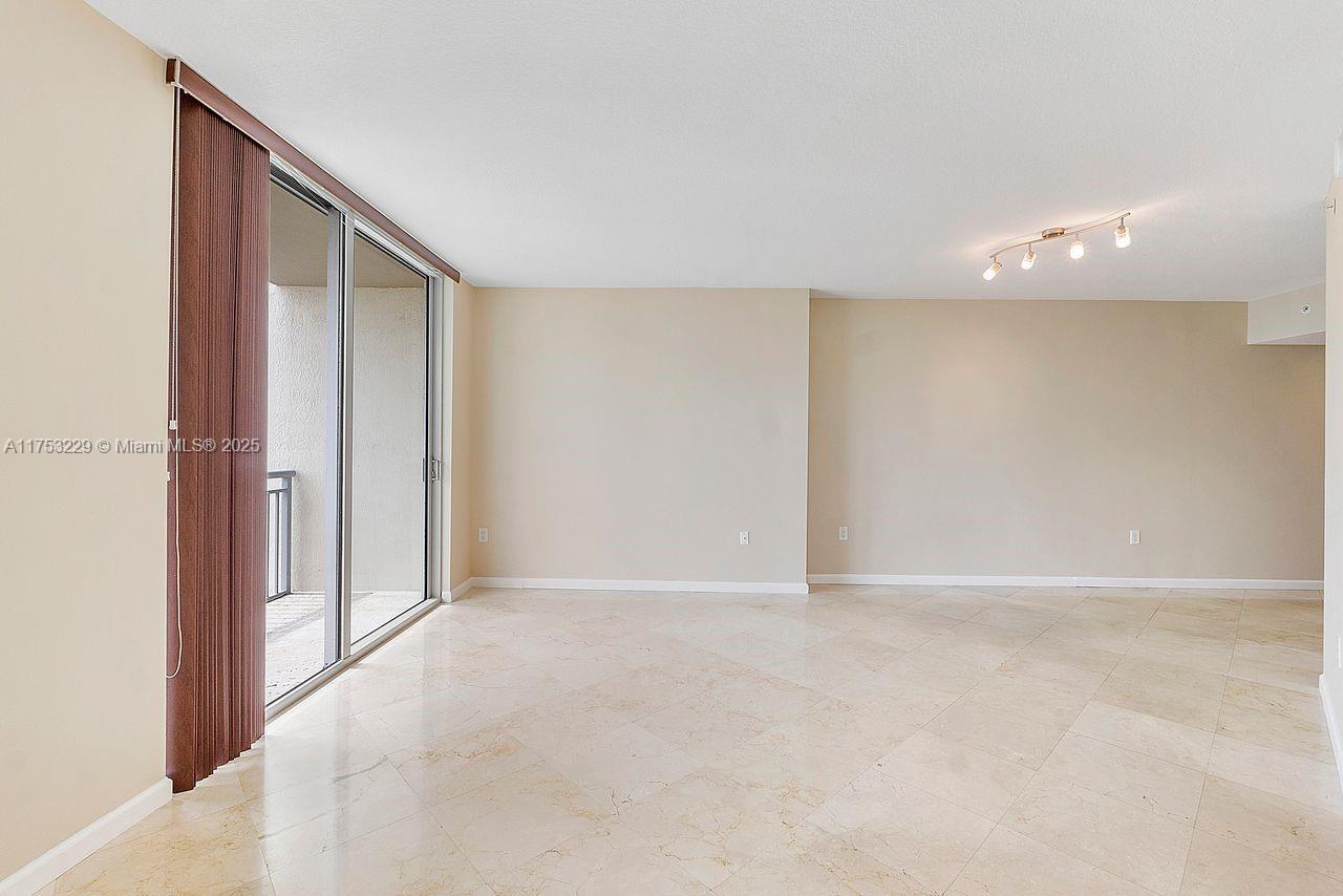 An empty room features beige walls, light-colored tile flooring, and a sliding glass balcony door — 9066 SW 73rd Ct # 1904, Miami FL 33156, MIAMI, FL