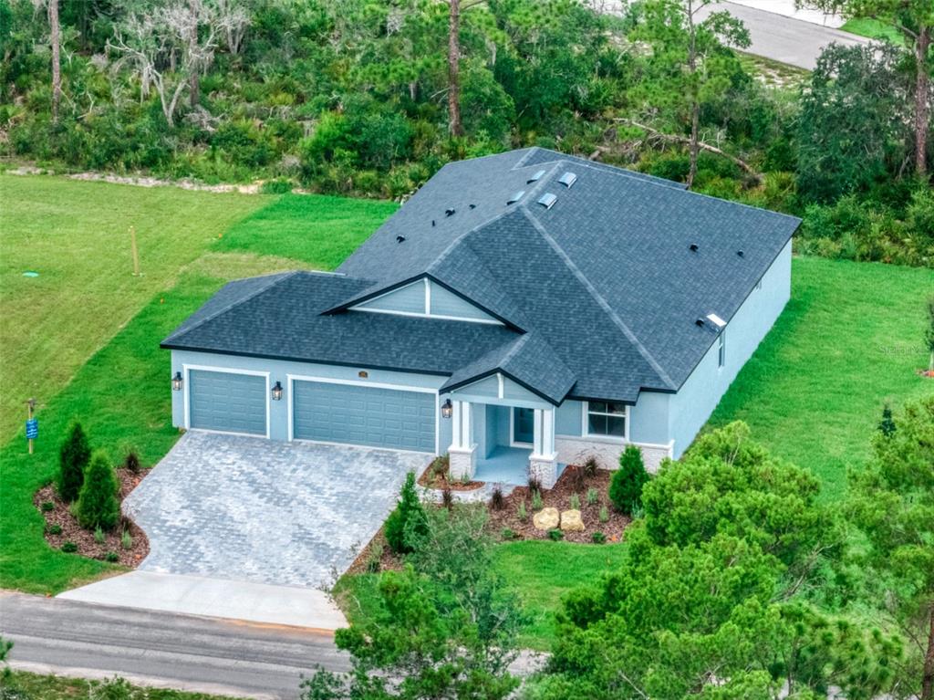 An aerial view of a single-story house with a gray exterior, shingled roof, and paver driveway — 4659 MIGNON DRIVE, SEBRING, FL