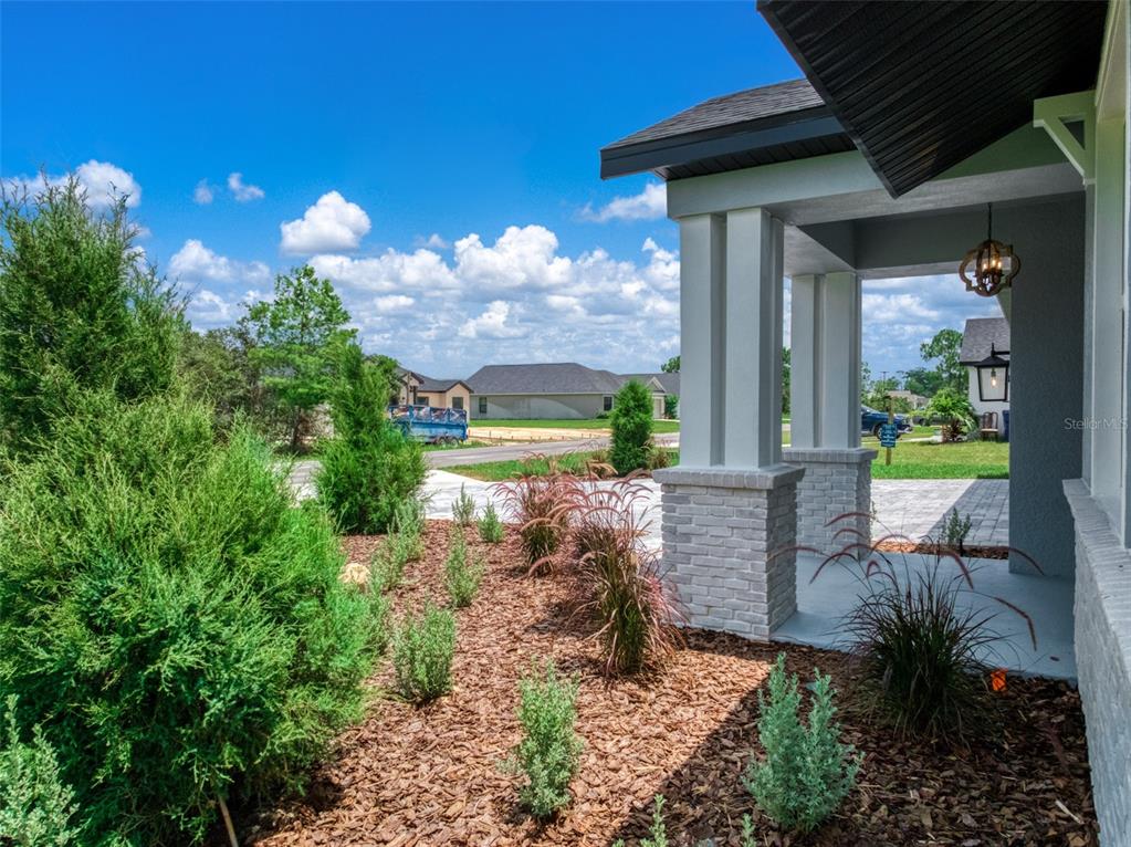 A view of a house exterior featuring a covered porch with stone columns and landscaping — 4659 MIGNON DRIVE, SEBRING, FL