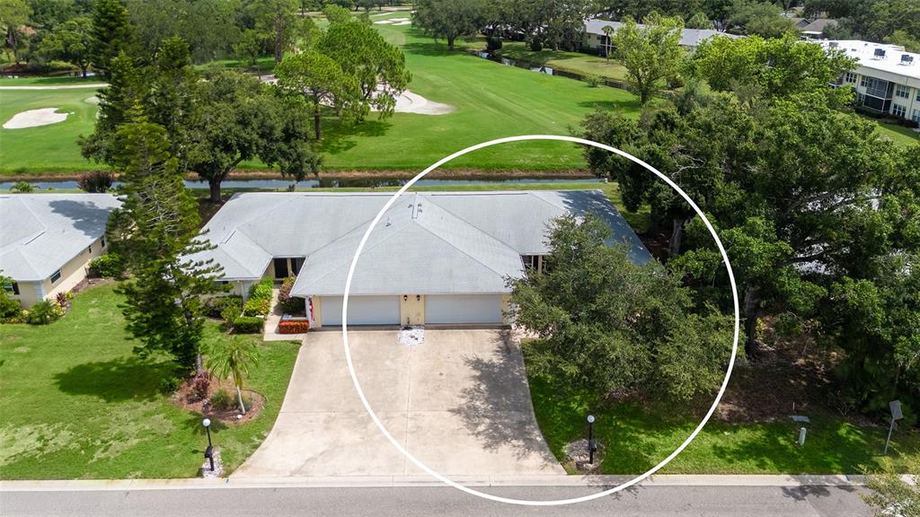 An aerial view of a single-story duplex with a shared driveway and a large tree — 5621 PALM AIRE DRIVE, SARASOTA, FL