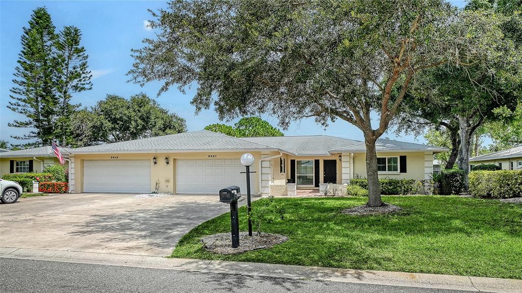 A single-story house with a two-car garage, a large tree, and a manicured lawn — 5621 PALM AIRE DRIVE, SARASOTA, FL