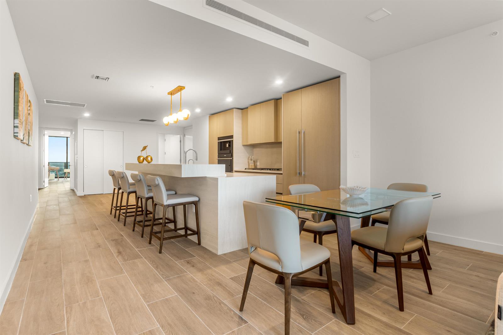 A modern kitchen and dining area with light wood cabinetry, a stone island, and tile flooring — 900 N Ocean Boulevard # 1904, Pompano Beach FL 33062, POMPANO BEACH, FL