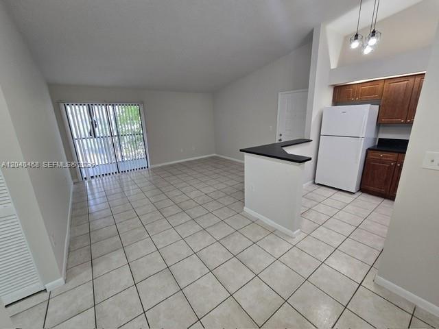 An open-concept living area features light-colored tile flooring and a kitchen with white appliances — HIALEAH, FL