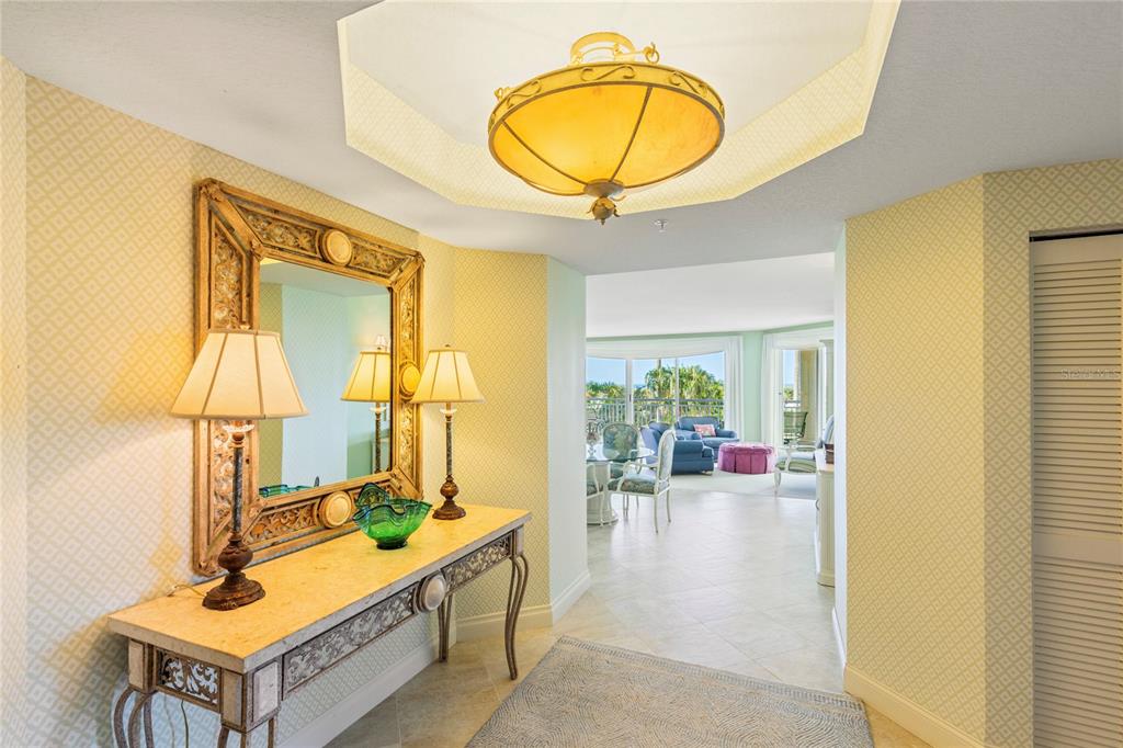 An entryway features a console table with a mirror, lamps, and a view into a living area — 1180 GULF BOULEVARD UNIT 202, CLEARWATER BEACH, FL