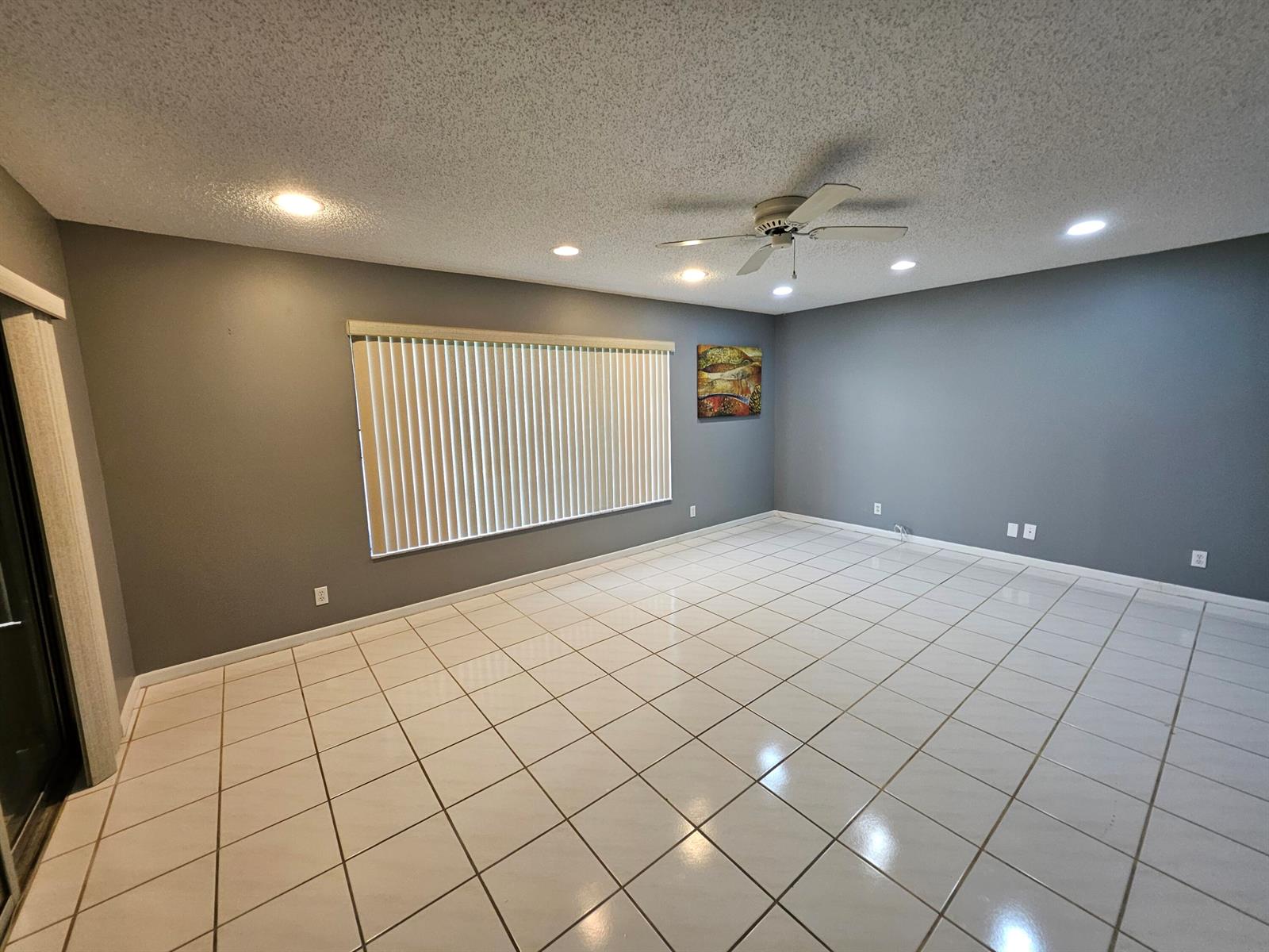 An empty room with gray walls, white tiled flooring, a ceiling fan, and large windows — 14628 Canalview Drive # A, Delray Beach FL 33484, DELRAY BEACH, FL