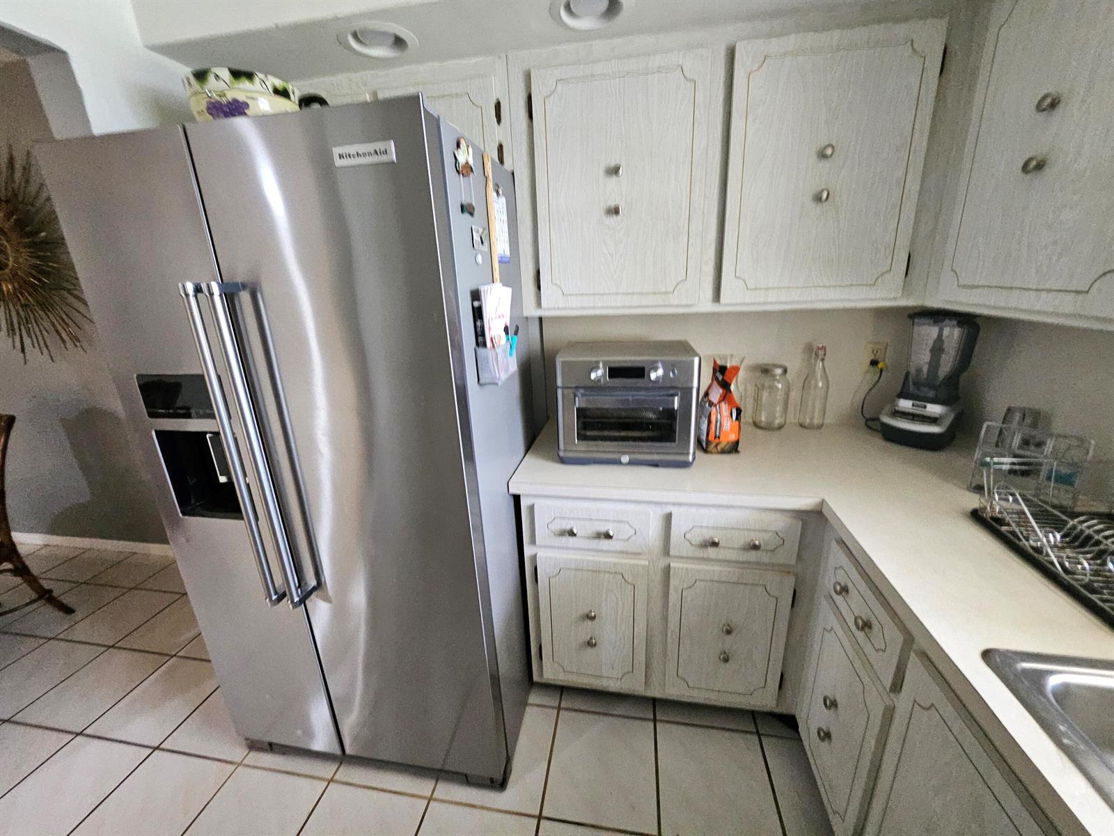A kitchen features a stainless steel refrigerator, light wood cabinets, and white countertops — 14628 Canalview Drive # A, Delray Beach FL 33484, DELRAY BEACH, FL