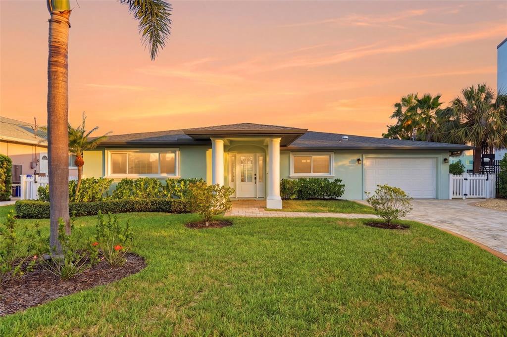 A light green single-story house with a white garage and two front porch columns — 7172 S SHORE DRIVE S, ST PETERSBURG, FL